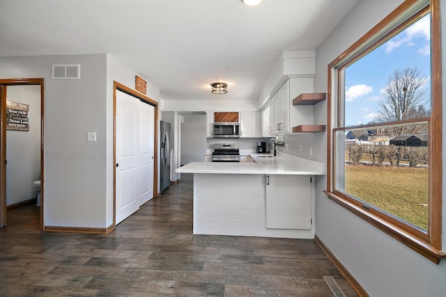 kitchen featuring sink, stainless steel appliances, white cabinets, dark hardwood / wood-style flooring, and kitchen peninsula