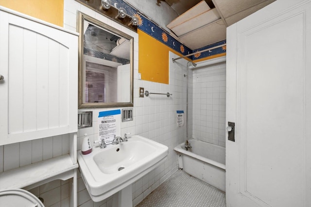 bathroom with tile patterned flooring, tiled shower / bath, sink, and tile walls