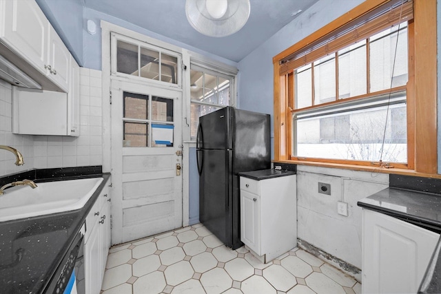 kitchen with white cabinetry, black fridge, a healthy amount of sunlight, and sink