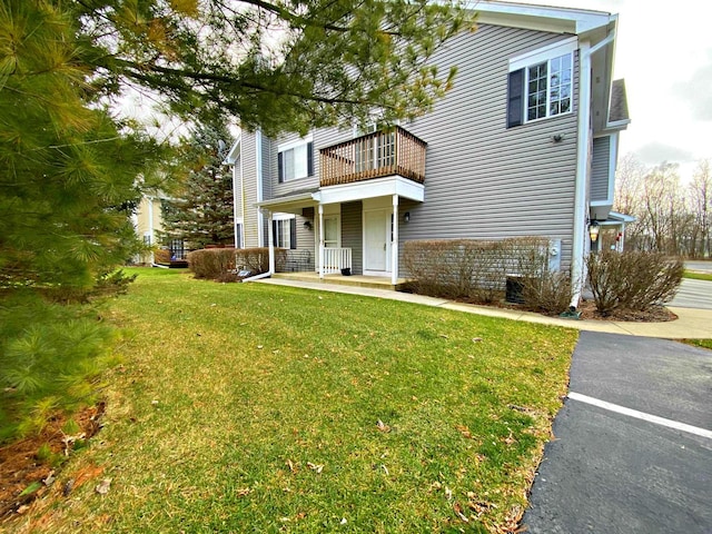 view of front of home with a balcony and a front lawn