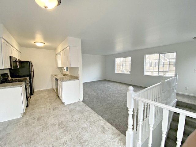 kitchen featuring white cabinetry, sink, light colored carpet, and stainless steel appliances