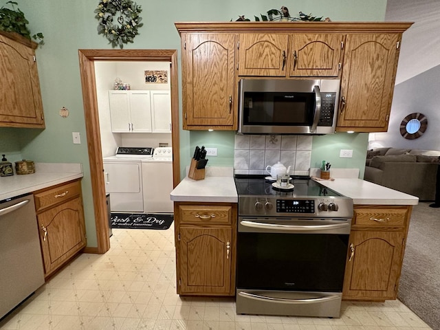 kitchen with washing machine and clothes dryer, appliances with stainless steel finishes, and decorative backsplash