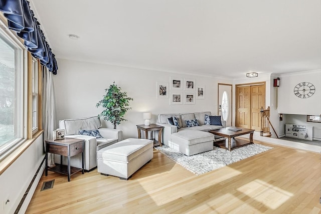 living room featuring a baseboard heating unit, ornamental molding, and light hardwood / wood-style floors