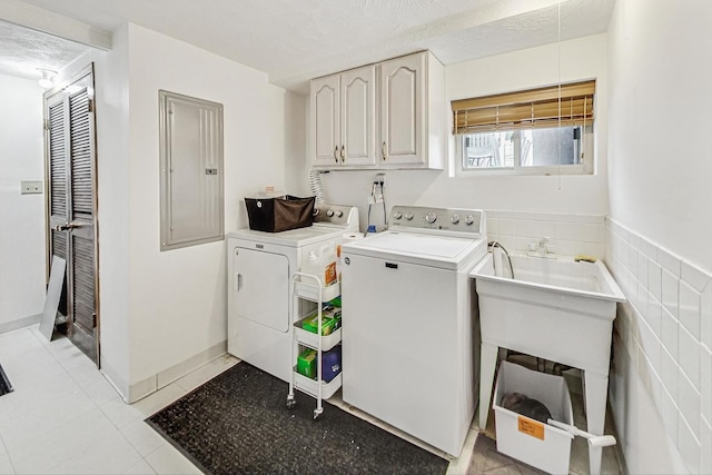 washroom with electric panel, cabinets, independent washer and dryer, a textured ceiling, and light tile patterned flooring