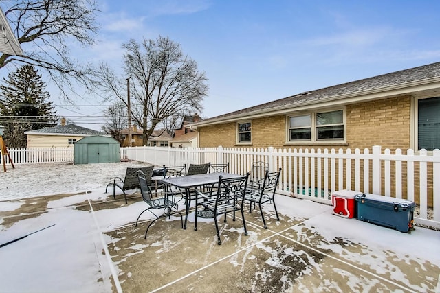 snow covered patio featuring a storage unit