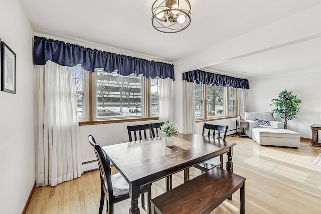 dining space with wood-type flooring, an inviting chandelier, and baseboard heating