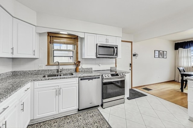 kitchen featuring white cabinetry, appliances with stainless steel finishes, light tile patterned flooring, and sink