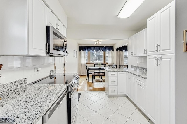 kitchen featuring light tile patterned floors, white cabinetry, electric range oven, light stone countertops, and kitchen peninsula