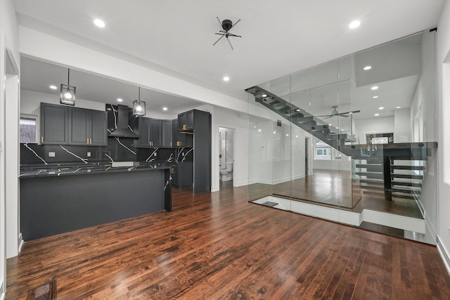 kitchen featuring dark hardwood / wood-style floors, decorative backsplash, ceiling fan, and wall chimney exhaust hood