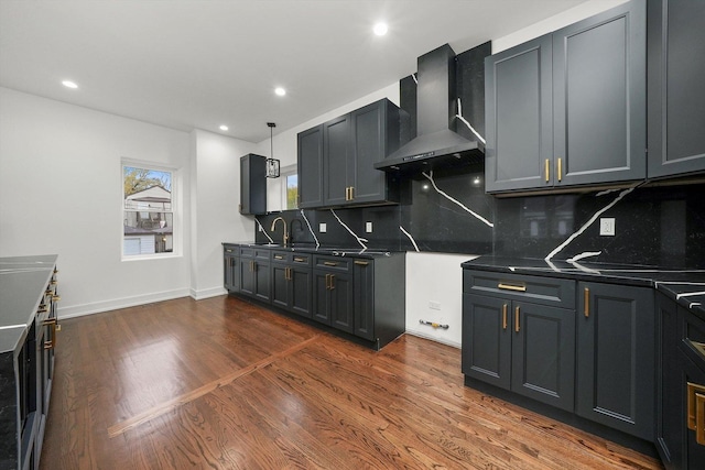 kitchen with decorative light fixtures, sink, decorative backsplash, dark wood-type flooring, and wall chimney range hood