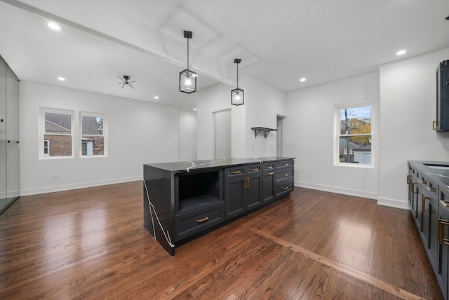 kitchen featuring ceiling fan, a kitchen island, dark hardwood / wood-style floors, and hanging light fixtures