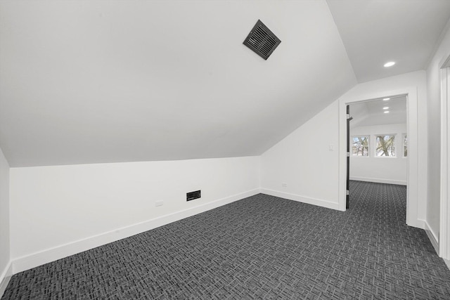 bonus room with dark colored carpet and lofted ceiling