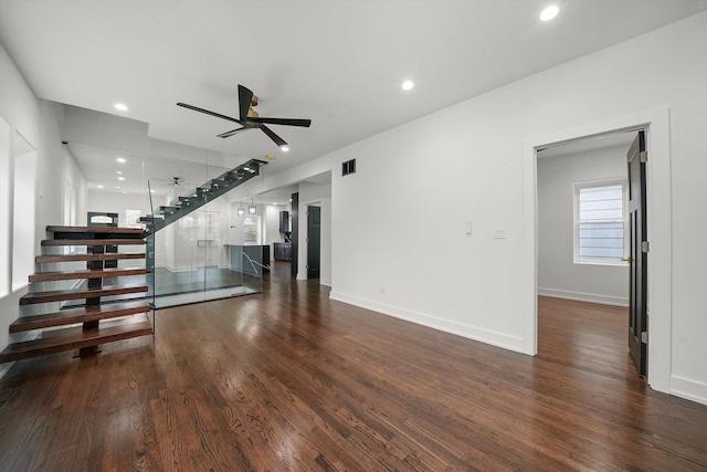 unfurnished living room featuring dark wood-type flooring and ceiling fan