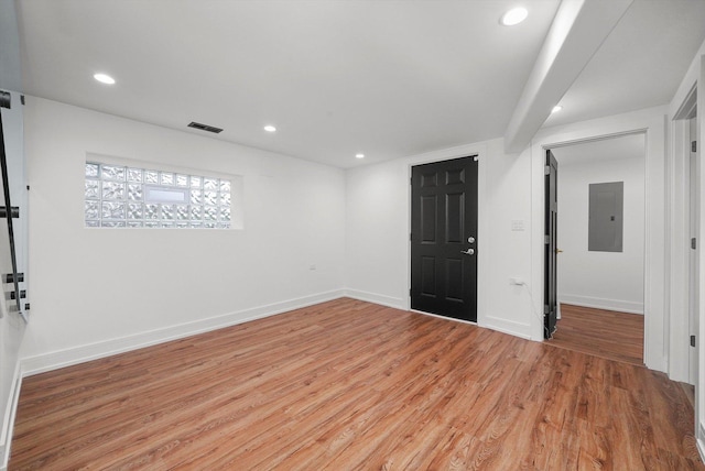 unfurnished room featuring electric panel and light hardwood / wood-style flooring