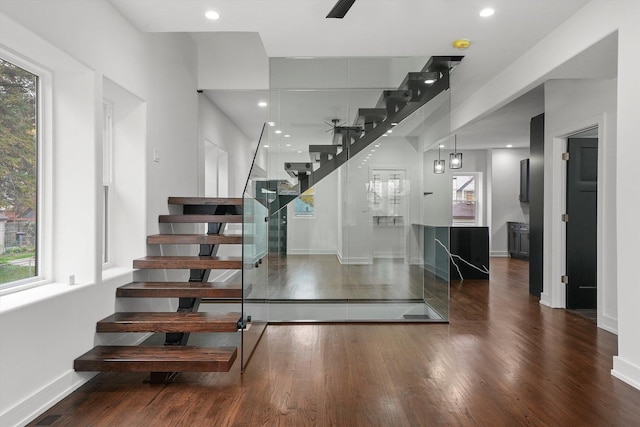 staircase with ceiling fan, plenty of natural light, and hardwood / wood-style floors