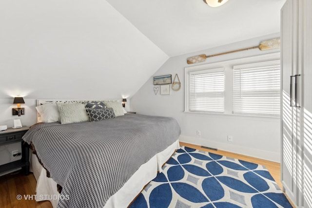 bedroom with lofted ceiling and wood-type flooring