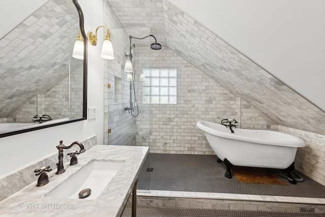 bathroom with vanity, independent shower and bath, vaulted ceiling, and tile walls