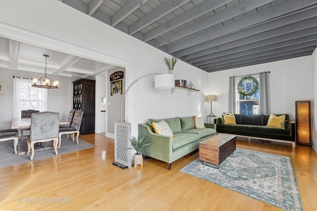 living room featuring beamed ceiling, a chandelier, and hardwood / wood-style floors