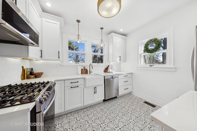 kitchen featuring pendant lighting, sink, backsplash, stainless steel appliances, and white cabinets