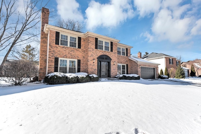 colonial-style house featuring an attached garage, a chimney, and brick siding