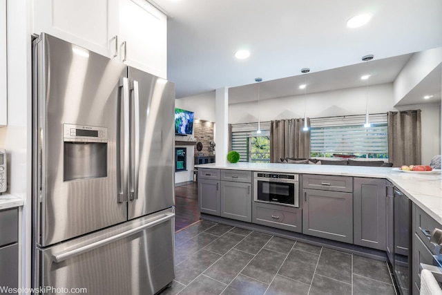 kitchen featuring gray cabinetry, light stone counters, hanging light fixtures, appliances with stainless steel finishes, and white cabinets