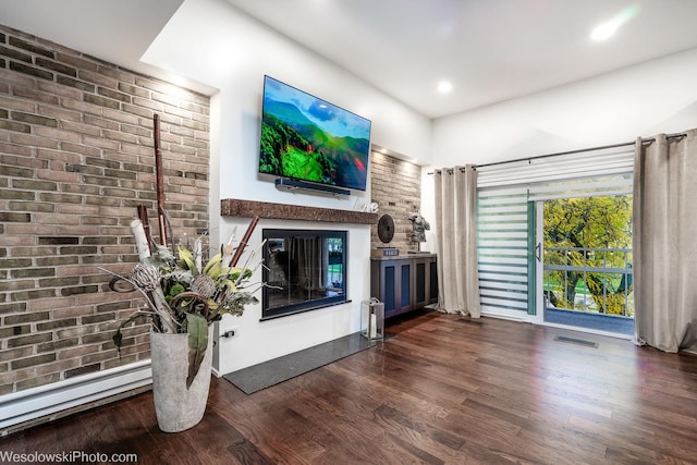 unfurnished living room with dark hardwood / wood-style flooring, a baseboard heating unit, and brick wall