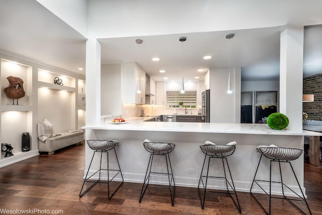 kitchen with tasteful backsplash, a kitchen breakfast bar, stainless steel fridge, kitchen peninsula, and white cabinets