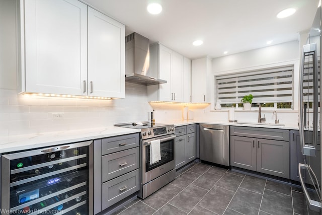 kitchen with gray cabinets, sink, wine cooler, stainless steel appliances, and wall chimney exhaust hood