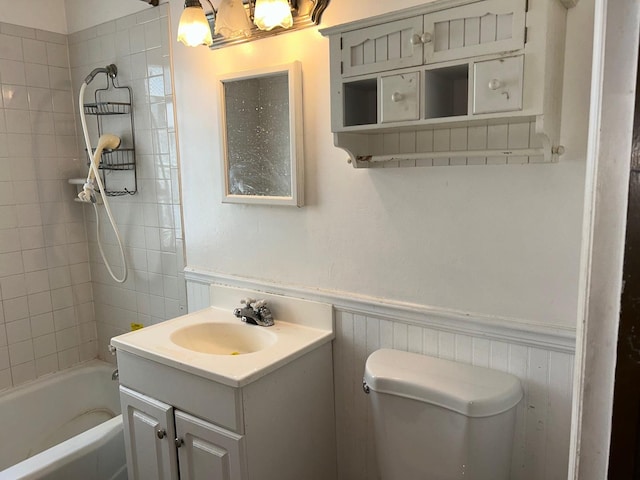 full bathroom featuring vanity, tiled shower / bath combo, and toilet