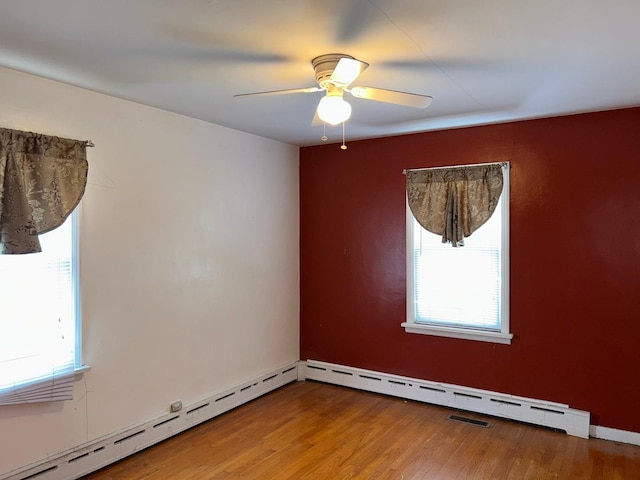 empty room featuring a baseboard heating unit, hardwood / wood-style flooring, and ceiling fan