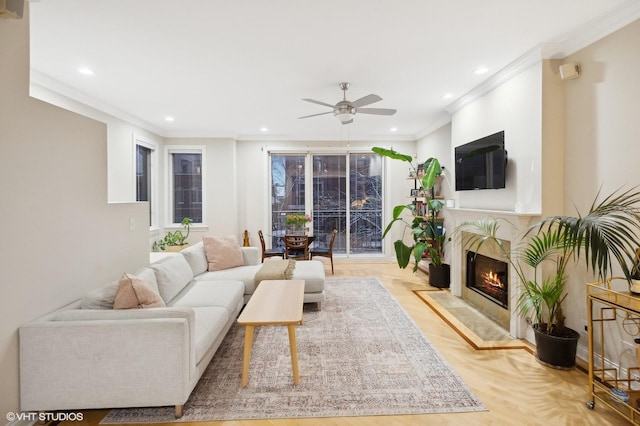 living room with a high end fireplace, ornamental molding, and ceiling fan