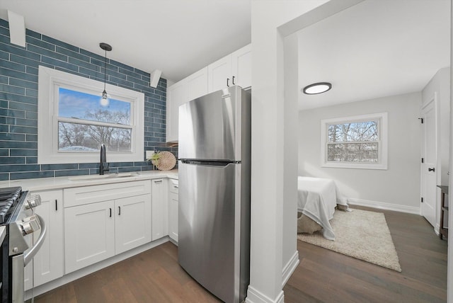 kitchen with appliances with stainless steel finishes, decorative light fixtures, tasteful backsplash, white cabinetry, and sink