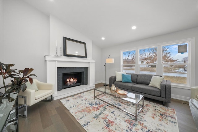 living room with lofted ceiling, a brick fireplace, dark wood-type flooring, and a wealth of natural light