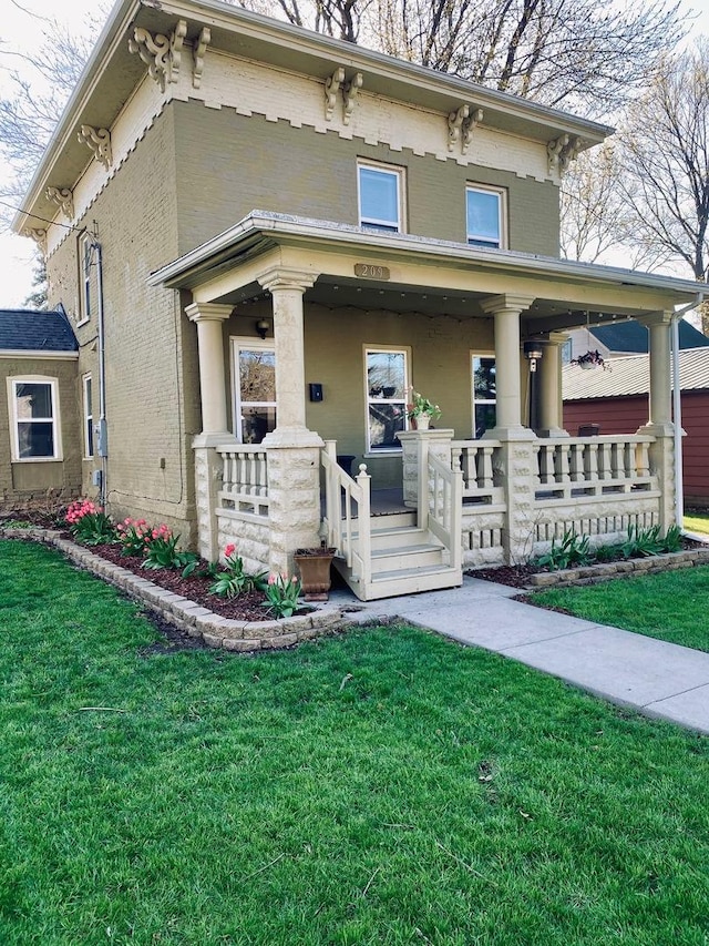 italianate home featuring covered porch, a front yard, and brick siding