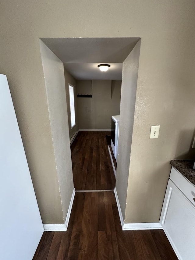 hallway featuring washer / dryer, baseboards, and wood finished floors