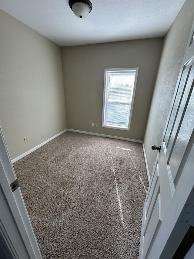 carpeted empty room featuring baseboards