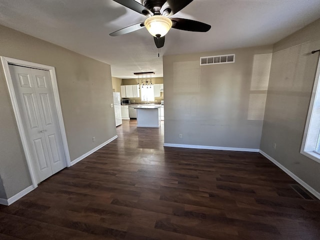 interior space with dark wood-style floors, visible vents, and baseboards