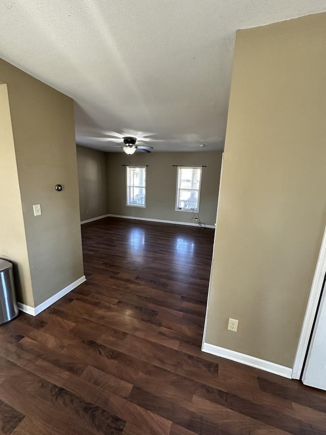 spare room with ceiling fan, a textured ceiling, dark wood finished floors, and baseboards