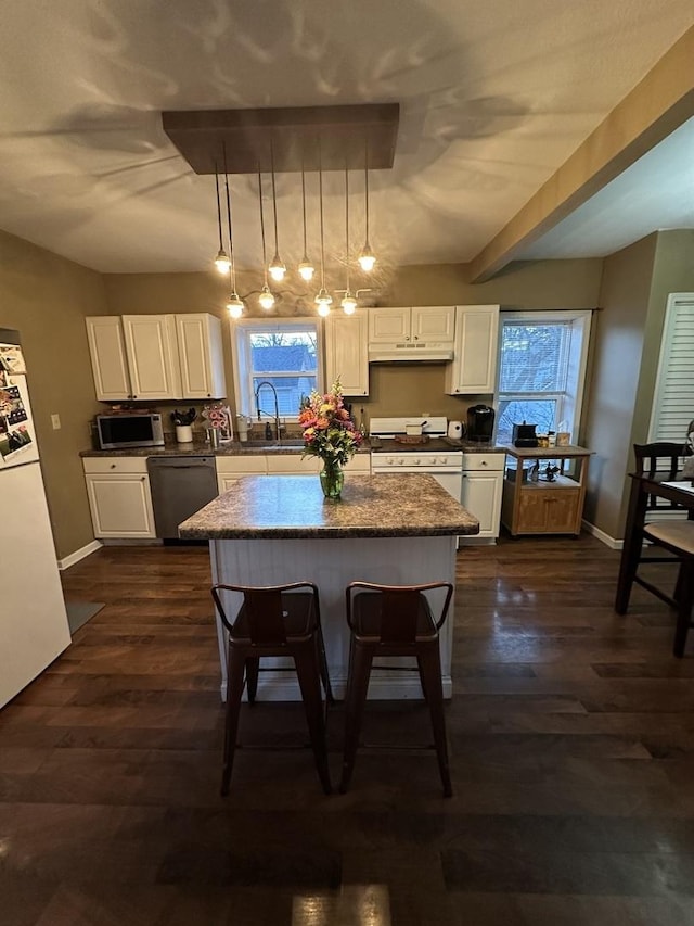 kitchen with appliances with stainless steel finishes, dark wood-style flooring, white cabinetry, and under cabinet range hood