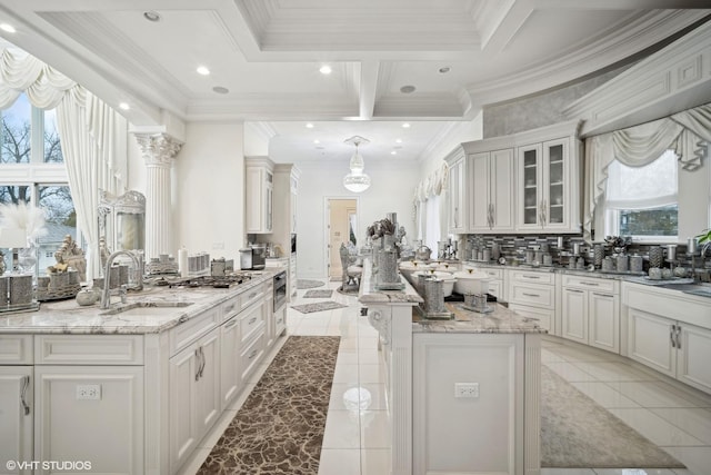 kitchen with a center island, sink, light stone countertops, and white cabinets