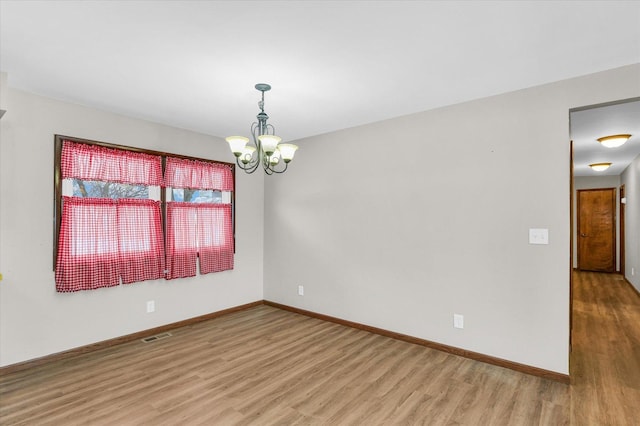 empty room with a chandelier and light hardwood / wood-style flooring