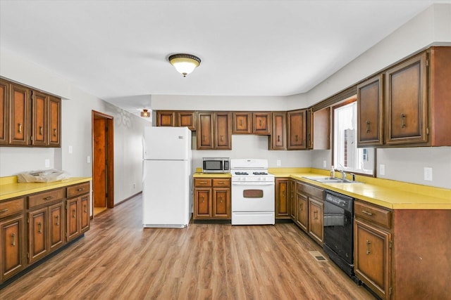 kitchen featuring white appliances, sink, and light wood-type flooring