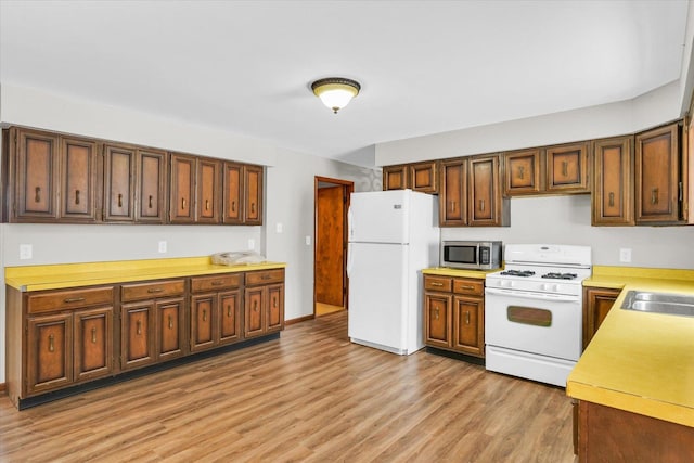 kitchen featuring light wood-type flooring, sink, and white appliances