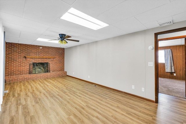 unfurnished living room with a fireplace, light hardwood / wood-style floors, ceiling fan, and a paneled ceiling