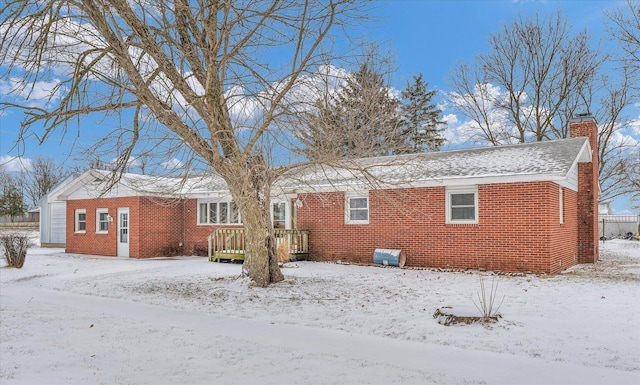 snow covered back of property featuring a deck