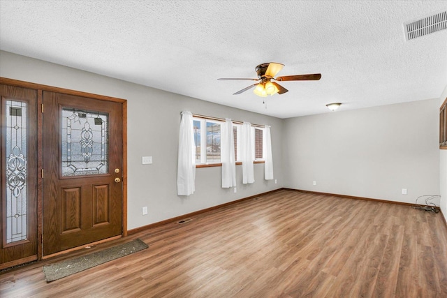 foyer with ceiling fan, a textured ceiling, and light wood-type flooring