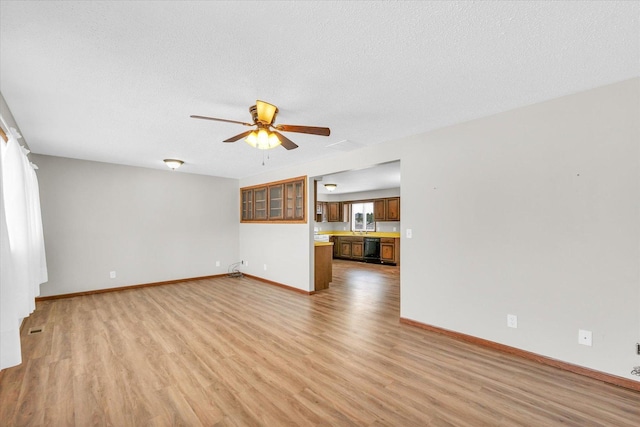 unfurnished living room featuring a textured ceiling, ceiling fan, and light wood-type flooring