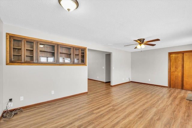 unfurnished room with ceiling fan, a textured ceiling, and light hardwood / wood-style floors