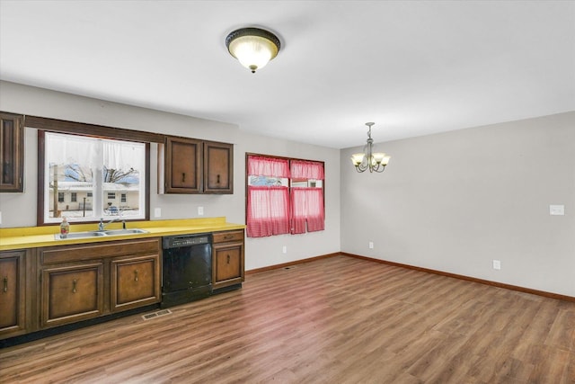 kitchen with sink, an inviting chandelier, hardwood / wood-style floors, hanging light fixtures, and black dishwasher