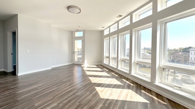 empty room with a healthy amount of sunlight and dark wood-type flooring